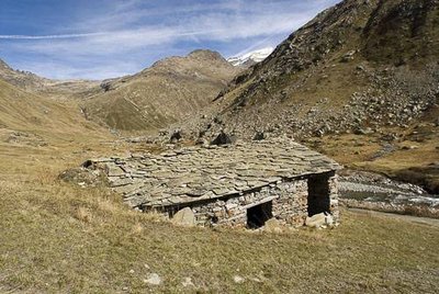 Grange en ruine, à demi enterrée dans la pente, adossée à un bloc rocheux. Bonneval sur Arc.