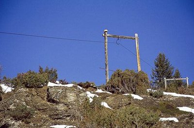 Portique supportant un ancien câble à foin au milieu de genévriers. Vue vers N.